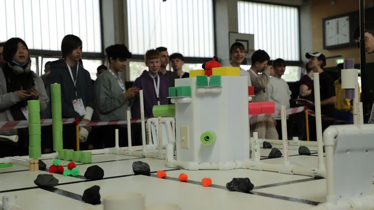 Students watching autonomous robots on the game table